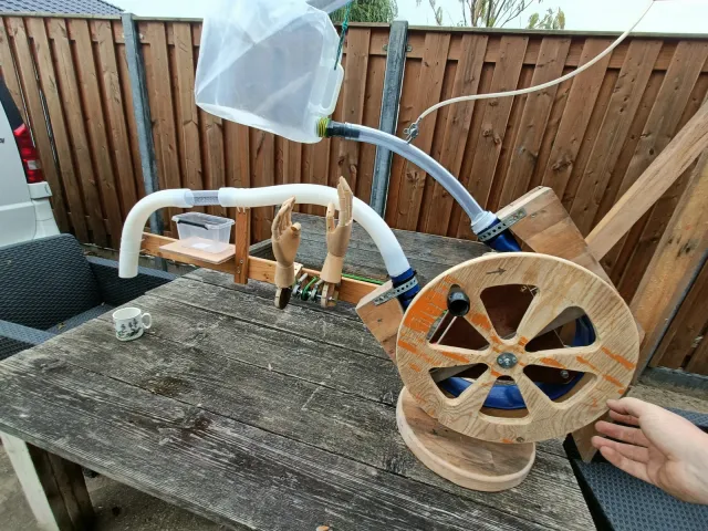 Houten draaimechaniek, slangen en twee modelhanden van de proefopstelling voor De Proefkeuken
