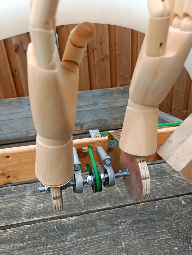 Detail van twee houten modelhanden op lagers met een groene aandrijfriem voor De Proefkeuken