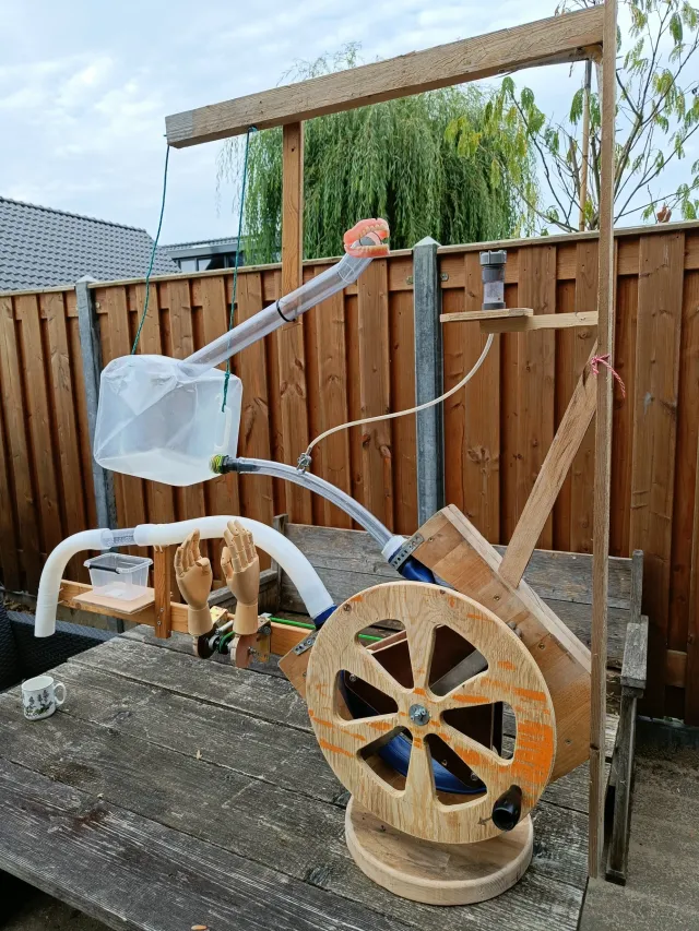 Complete proefopstelling voor De Proefkeuken met houten frame, gebit, slangen, modelhanden en een groot draaiwiel