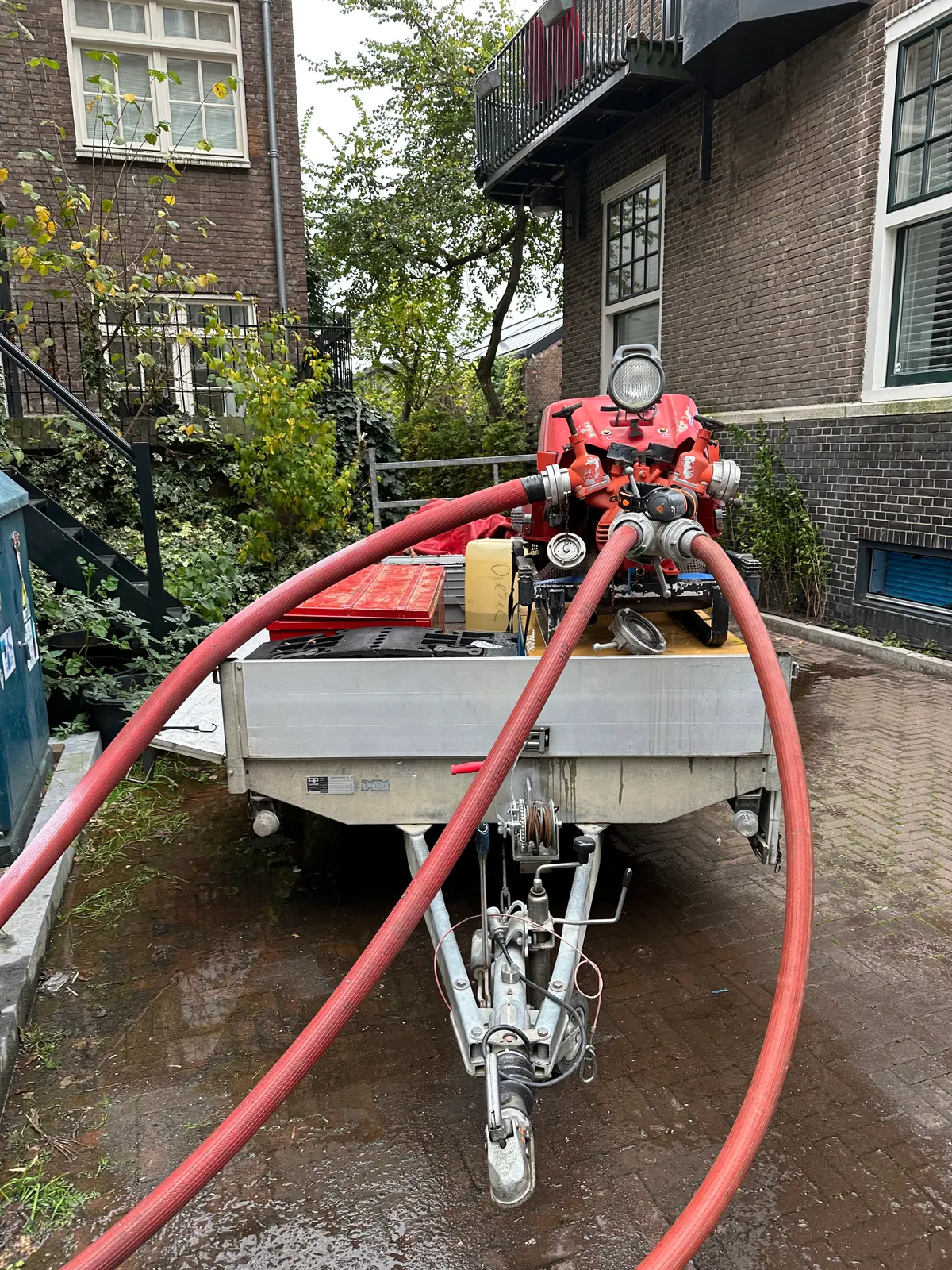 Rode waterpomp en aangesloten slangen op een aanhanger tijdens de voorbereiding van Amsterdamned 2