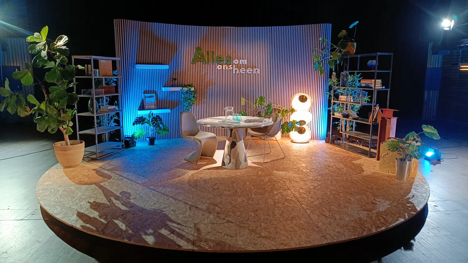 Rond houten podium met tafel, stoelen, planten en gebogen achterwand voor Circl – Alles om ons heen