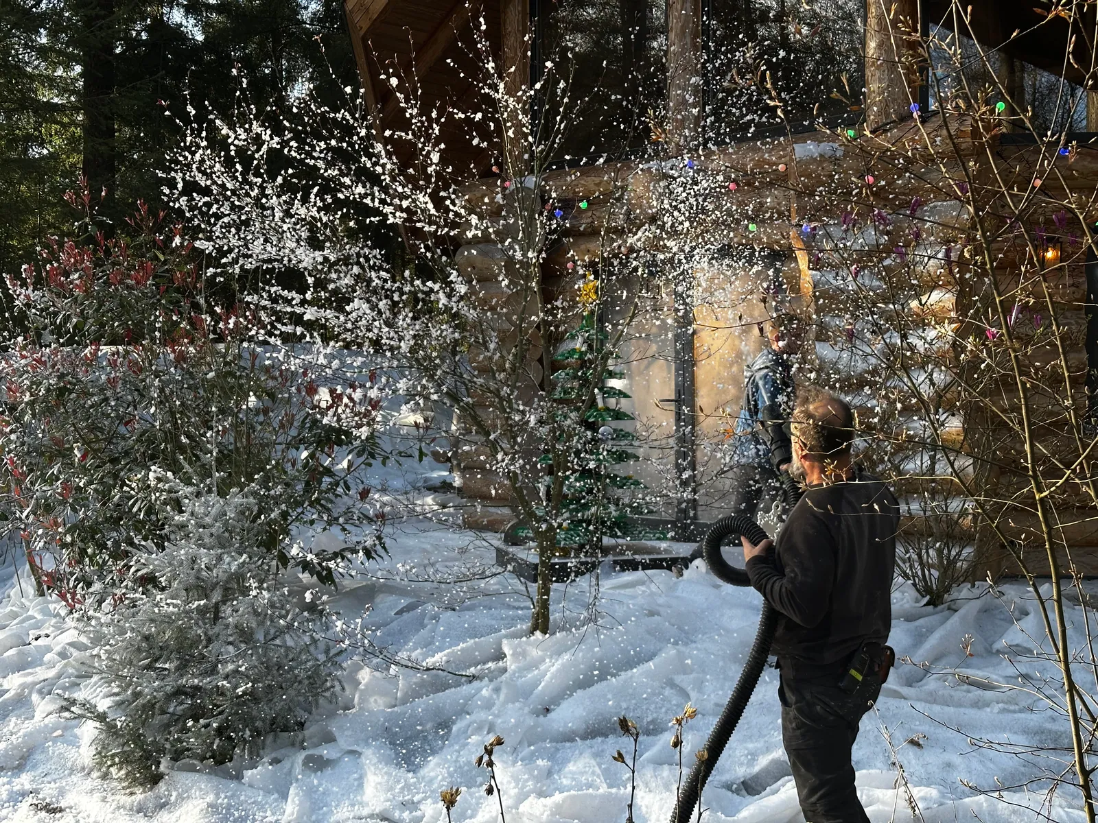 Sneeuwvlokken worden met een slang aangebracht tussen de bomen op de filmset